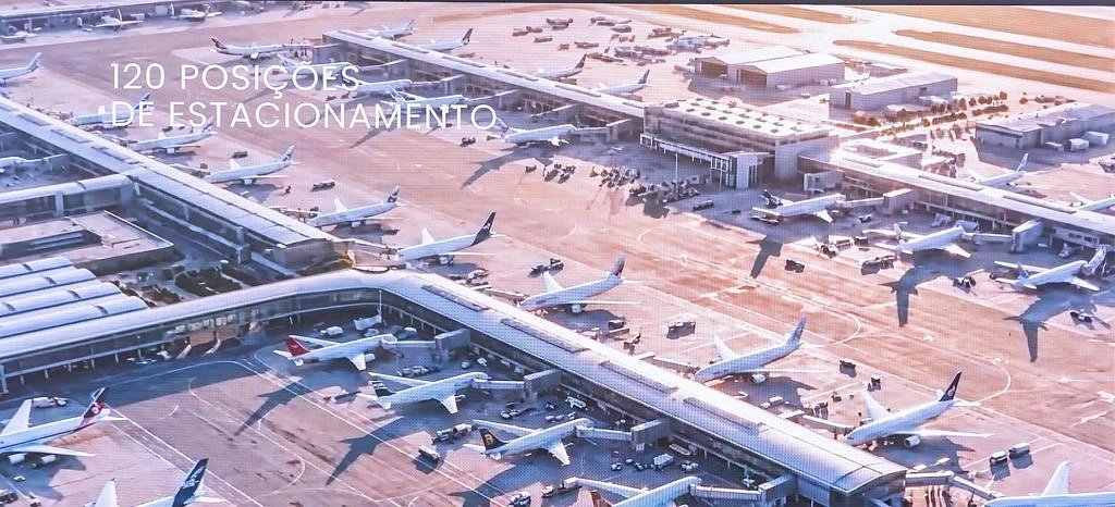 Computer-generated aerial view of terminal piers with many aircraft parked at boarding bridges and on the apron.