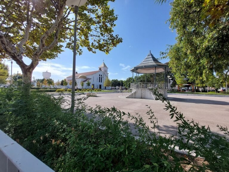 Town square with trees, a white church and an octagonal bandstand.