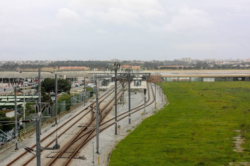 Plataformas e linhas de uma estação ferroviária sob céu nublado.