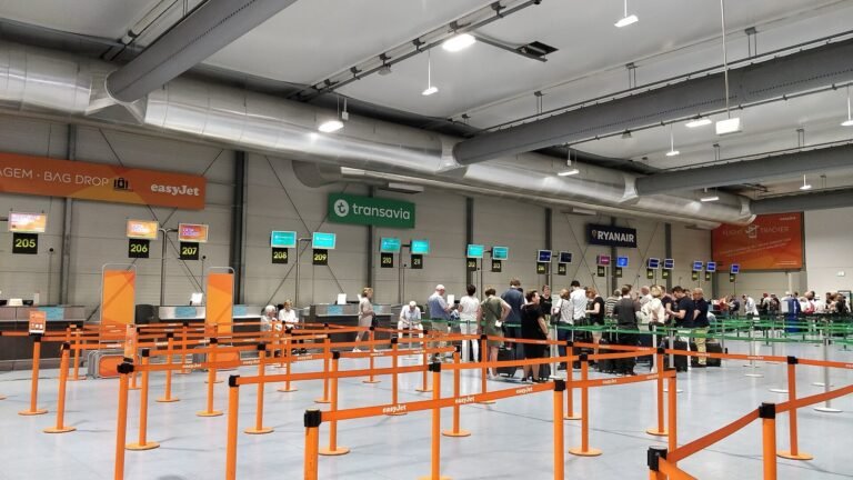 Low, modern terminal building with a car park in front.