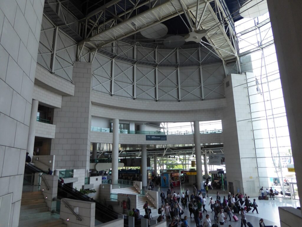 Exterior of a large airport terminal building with a covered drop-off area.
