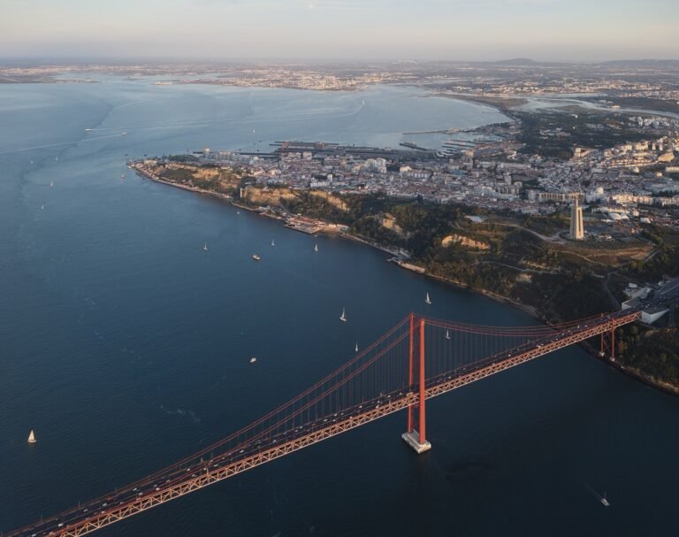 View from an aircraft window of a red suspension bridge and dense city below.